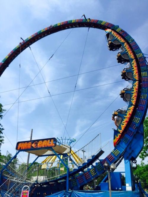 A colorful amusement park ride called "Fireball" with riders suspended upside down on a large circular track.