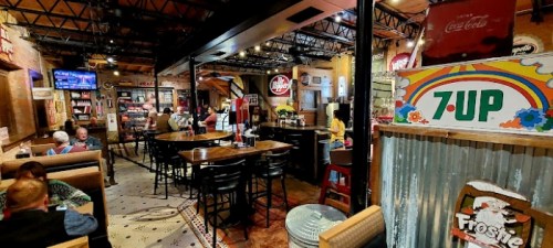 A cozy restaurant interior with wooden tables, vintage soda signs, and patrons enjoying their meals.