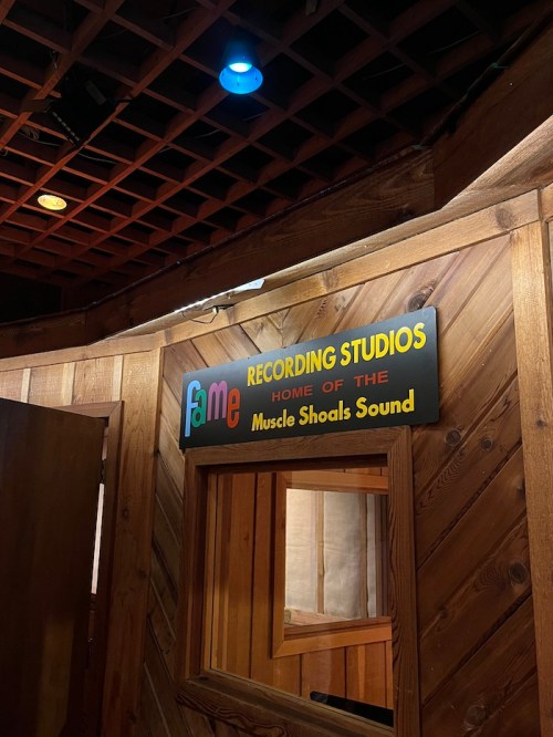 Sign for Fame Recording Studios, home of the Muscle Shoals Sound, displayed on a wooden wall.