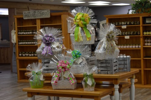 A display of gift baskets wrapped in cellophane with colorful bows, set in a rustic store interior.