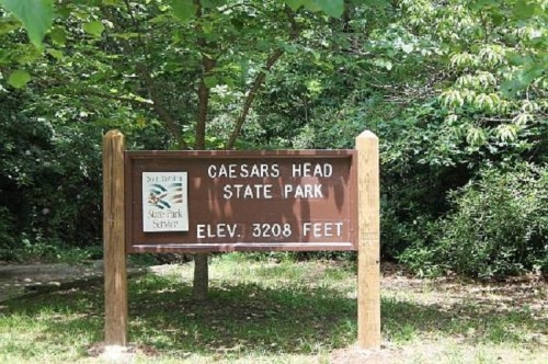 Sign for Caesars Head State Park, indicating an elevation of 3208 feet, surrounded by greenery.