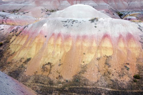 Colorful, layered hills with shades of red, yellow, and gray, showcasing unique geological formations and sparse vegetation.