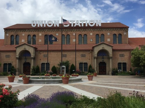 Historic Union Station building with a large sign, surrounded by gardens and a cloudy sky.