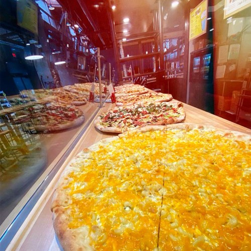 A display of large pizzas, one topped with cheese and the other with various toppings, in a restaurant setting.