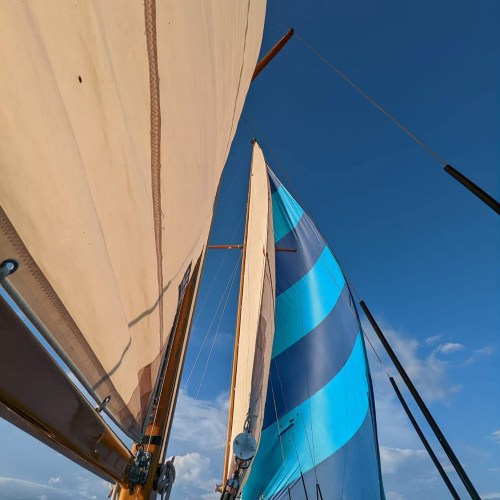 Sails of a boat against a clear blue sky, showcasing vibrant colors and textures.