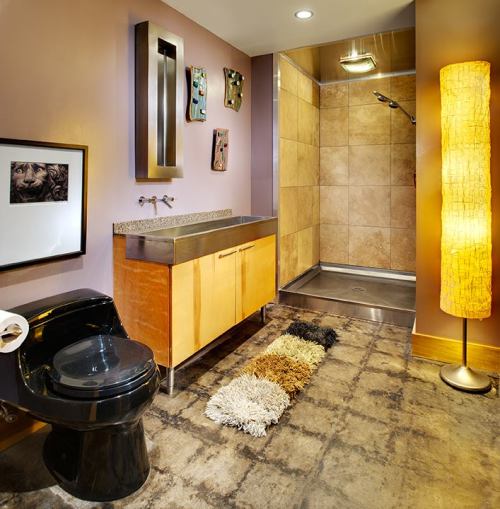 Modern bathroom featuring a black toilet, wooden vanity, shower, and a textured rug on a concrete floor.