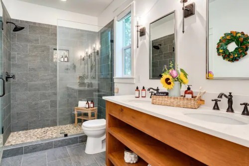 Modern bathroom featuring a glass shower, wooden vanity, and decorative accents like a wreath and sunflowers.