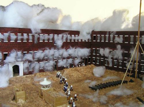A detailed model of a historical scene with soldiers, cannons, and smoke effects around a brick building.