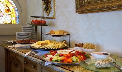 A beautifully arranged buffet with fruits, cheeses, cookies, and snacks on a table near a stained glass window.