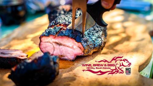 A close-up of a smoked meat brisket being sliced on a wooden board, with a logo for Wine, Brew & BBQ in Hill City, SD.