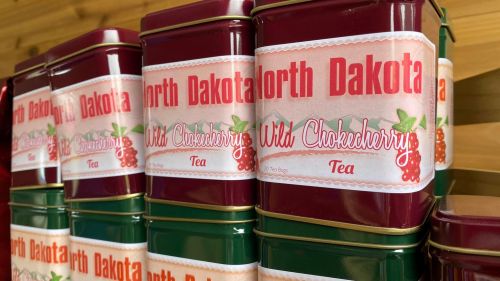 A stack of tea tins labeled "North Dakota Wild Chokecherry Tea" with a red and white design.