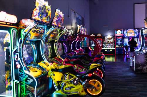 A vibrant arcade filled with colorful racing game machines and neon lights.