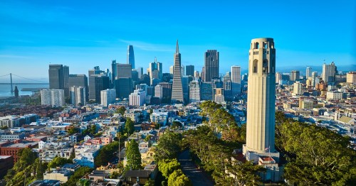 A panoramic view of San Francisco, featuring the skyline, Coit Tower, and the Golden Gate Bridge in the background.