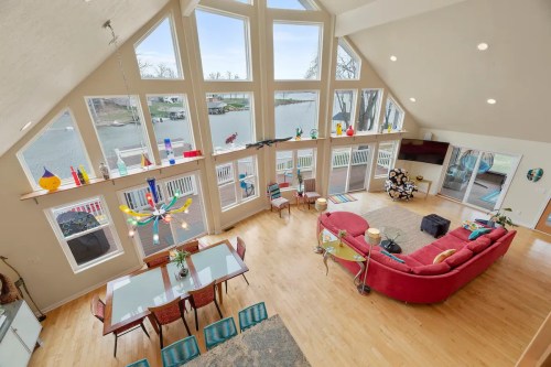 Spacious, modern living area with large windows, colorful decor, and a view of the water. Bright and inviting atmosphere.