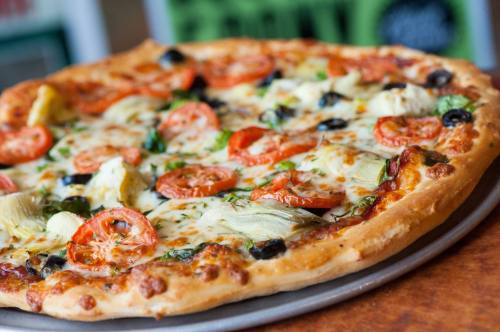 A delicious pizza topped with tomatoes, olives, artichokes, and herbs on a golden crust.