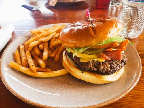 A juicy burger with lettuce, tomato, and mustard, served with a side of crispy fries on a plate.