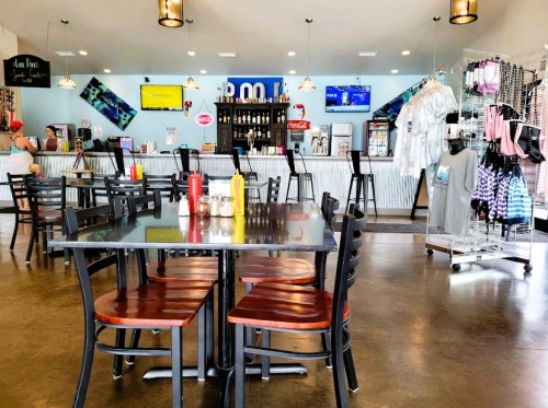 A casual dining area with black chairs, a bar counter, and a display of merchandise in a bright, inviting space.