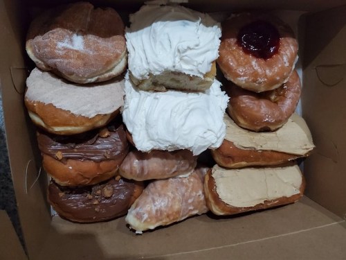 A box filled with assorted donuts, including frosted, glazed, and filled varieties.