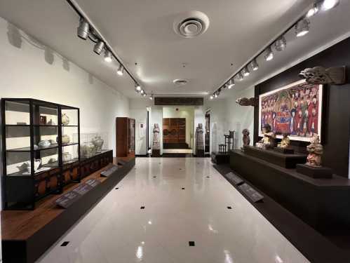 A museum interior featuring display cases with artifacts, sculptures, and a large mural on the wall.