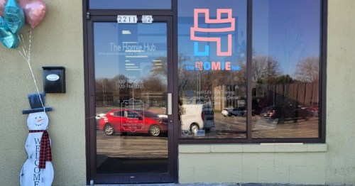 Exterior view of The Homie Hub entrance, featuring a welcoming sign and festive decorations.