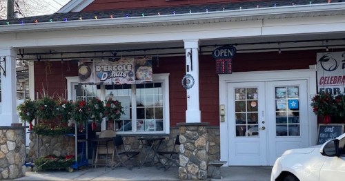 A cozy donut shop with a red exterior, festive decorations, and an "Open" sign displayed.