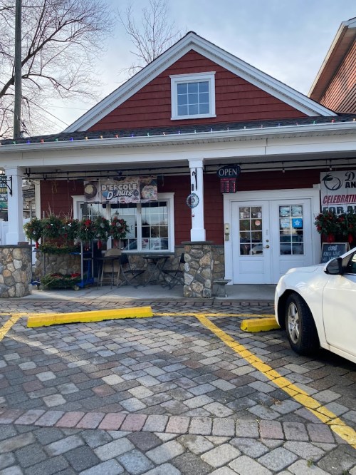 A red and white building with a stone facade, decorated for the holidays, featuring an open sign and outdoor seating.
