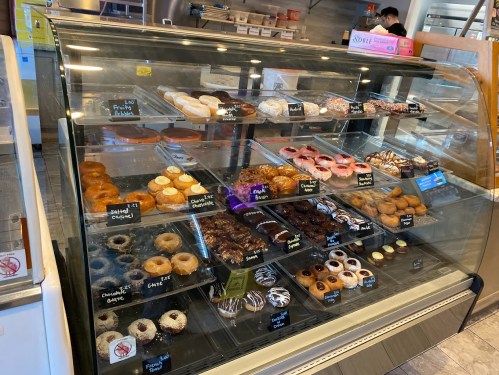 A display case filled with various donuts, including glazed, chocolate, and sprinkled varieties.