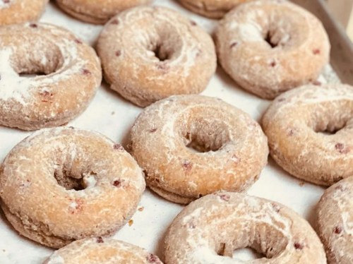 A close-up of freshly baked, powdered sugar-coated donuts arranged in a tray.