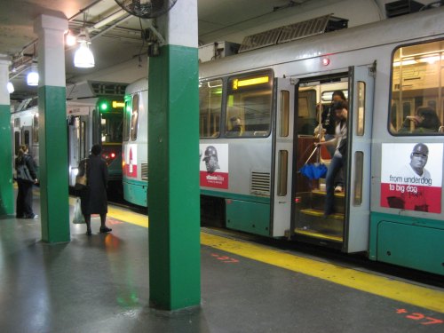 A subway station with trains arriving and departing, passengers boarding and alighting, and green lights illuminating the scene.