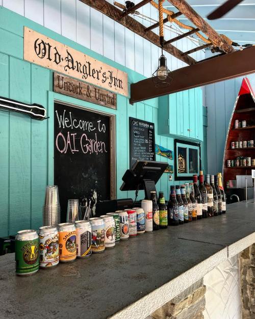 A bar counter with various beer cans and bottles, set in a colorful, coastal-themed establishment.