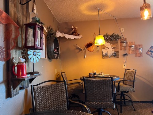 Cozy café interior with rustic decor, including tables, wall art, and warm lighting.