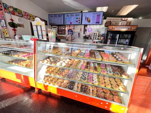 A display case filled with a variety of colorful donuts and pastries in a bright, inviting donut shop.