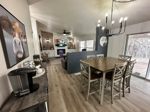 Cozy dining area with a wooden table, modern decor, and a view of a living space featuring a TV and large windows.