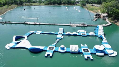 Aerial view of a large inflatable water park on a lake, featuring various slides and obstacles.