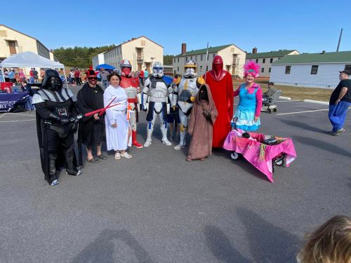 A group of people in Star Wars costumes, including Darth Vader, stormtroopers, and various characters, posing outdoors.