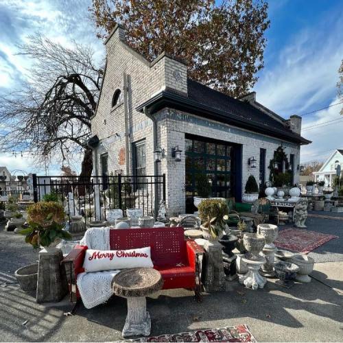 A charming building with a festive "Merry Christmas" sign, surrounded by decorative planters and outdoor decor.