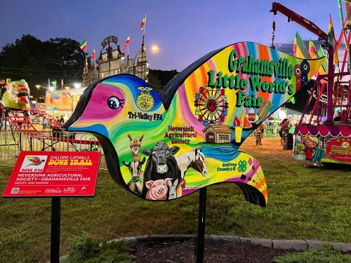 Colorful sign for the Grahamsville Little World's Fair, featuring farm animals and carnival attractions in the background.