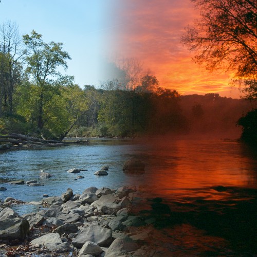A serene river scene split between a bright blue sky and a vibrant sunset, with rocks and trees lining the water.