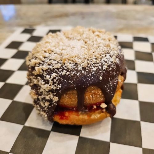 A delicious dessert featuring a cookie sandwich with chocolate drizzle and a sprinkle of powdered sugar on top.