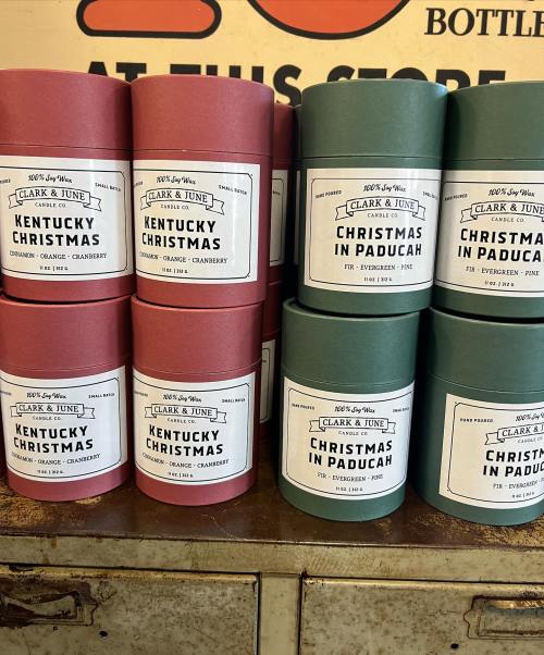 A display of colorful cylindrical containers labeled "Kentucky Christmas" and "Christmas in Paducah" on a shelf.