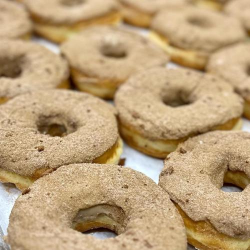 A close-up of freshly baked donuts coated in cinnamon sugar, arranged neatly on a tray.
