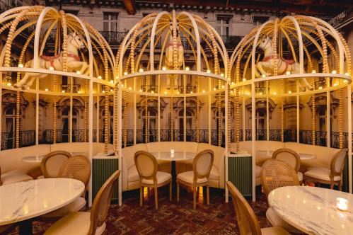 Elegant restaurant interior featuring carousel horse decor, soft lighting, and round tables with wicker chairs.