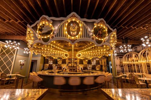 A stylish bar with a circular design, adorned with mirrors and bright lights, set in an elegant dining space.