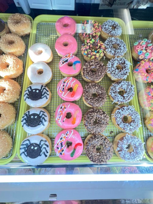 A variety of colorful donuts displayed on a tray, including sprinkles, chocolate, and themed designs.