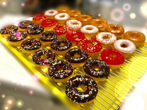 A colorful assortment of donuts on a cooling rack, featuring various glazes and sprinkles.