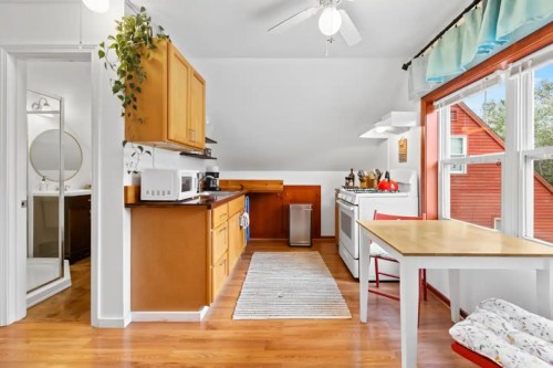 Bright kitchen with wooden cabinets, a dining table, and large windows, featuring a cozy, inviting atmosphere.