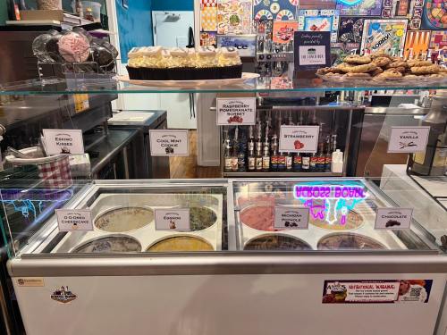 A display case filled with various ice cream flavors and desserts, labeled with names like "Oreo Cheesecake" and "Strawberry."