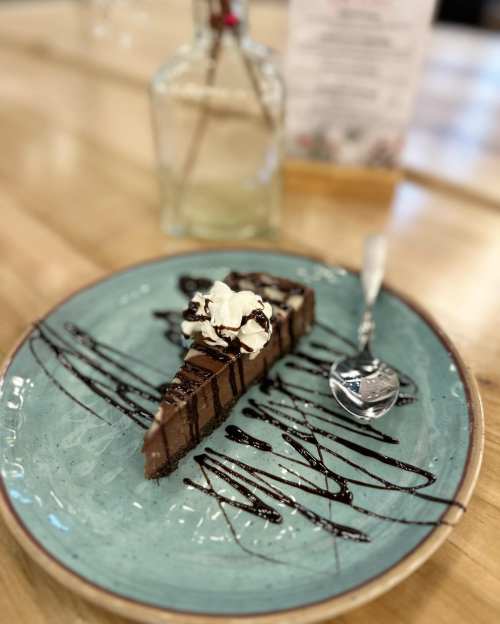 A slice of chocolate cake topped with whipped cream and drizzled with chocolate sauce on a blue plate.