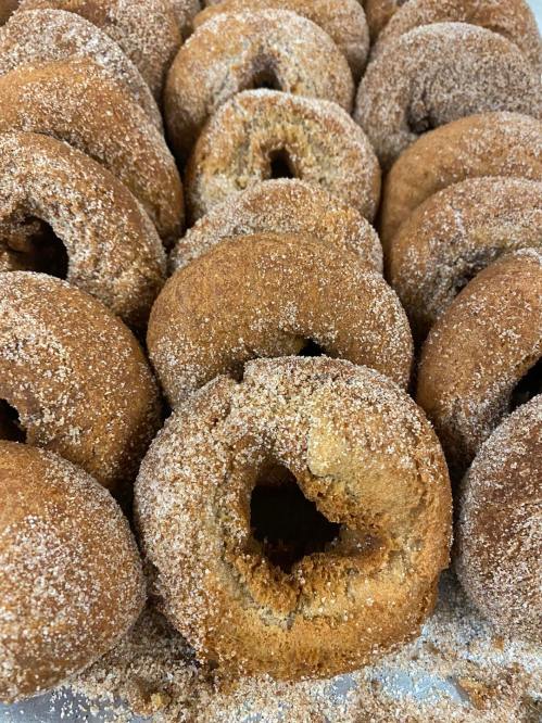 A close-up of freshly baked, cinnamon-sugar-coated donuts arranged closely together.