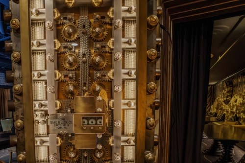 Close-up of a large, ornate safe door with intricate locking mechanisms and a vintage label.